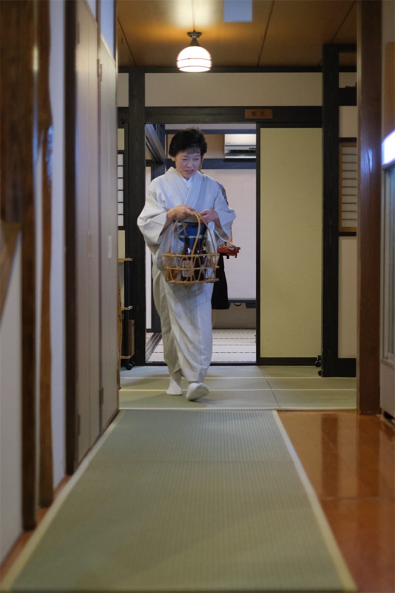 お盆を手に、畳廊下をゆく女将